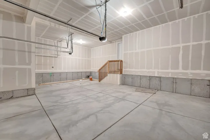 Spacious garage featuring a concrete floor, exposed drywall with taped seams, and a partially finished ceiling