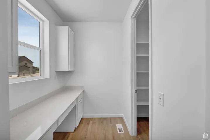 Built-in desk area featuring a long countertop, under-counter cabinetry, and a wall-mounted cabinet