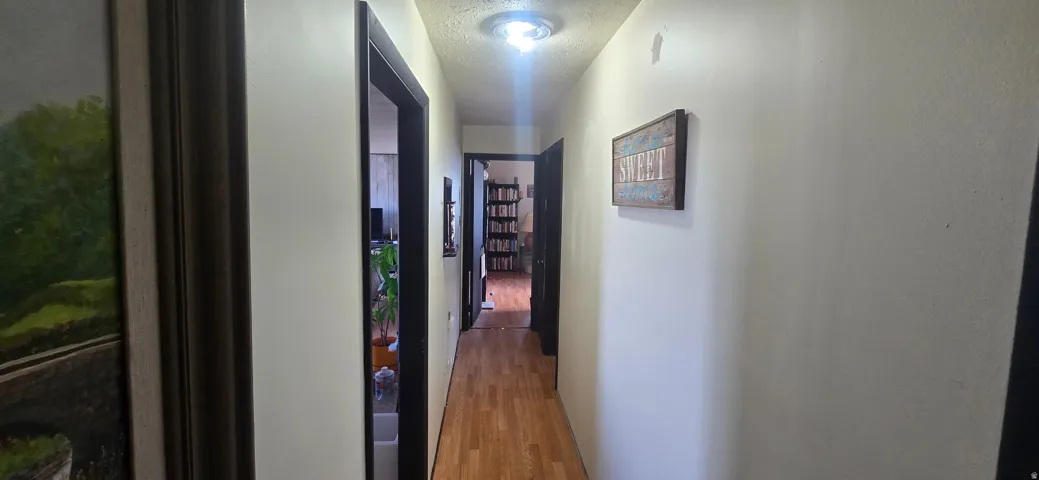 Hallway featuring wood-finish flooring, light-toned walls, and dark door frames