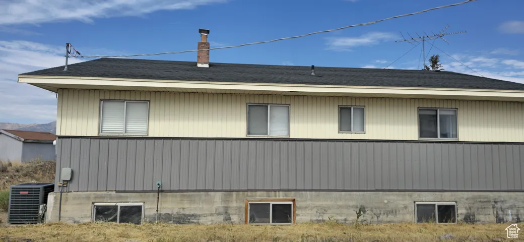 Exterior siding featuring a two-tone design with beige vertical panels over gray corrugated metal