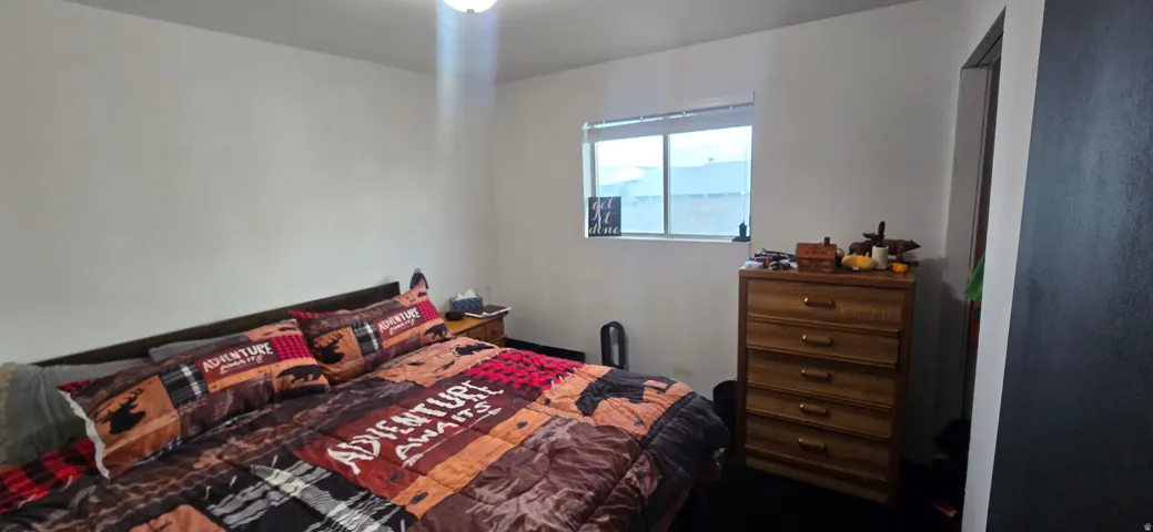 Bedroom featuring a window with blinds, overhead lighting, and dark-colored carpeting