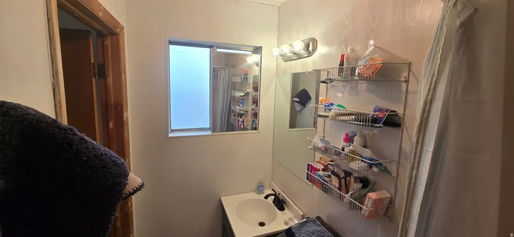 Bathroom featuring a vanity with an integrated sink, a wall-mounted light fixture, and a window