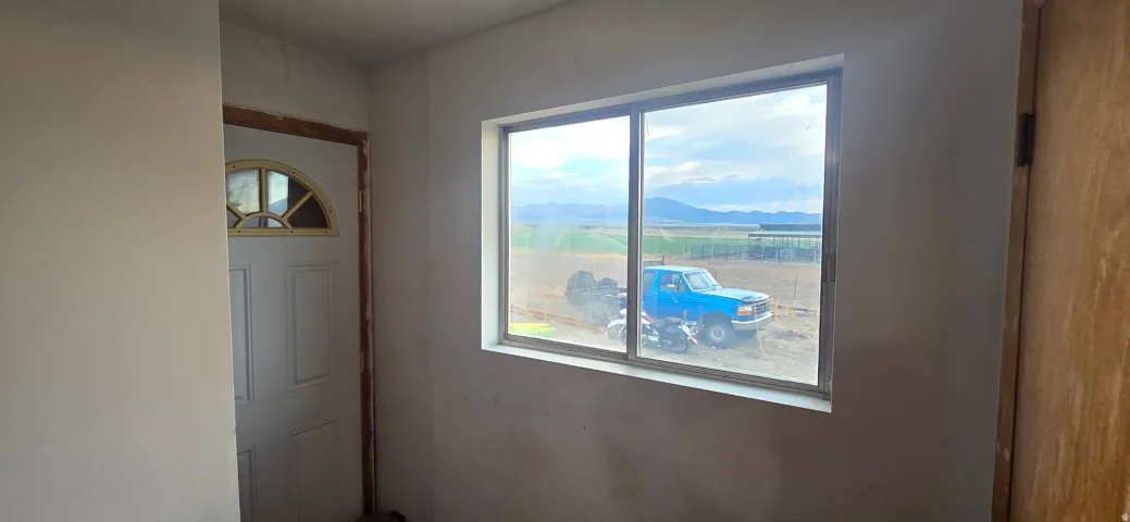Interior space featuring a window with aluminum framing, a solid exterior door with an arched window insert, and a wood-finish interior door