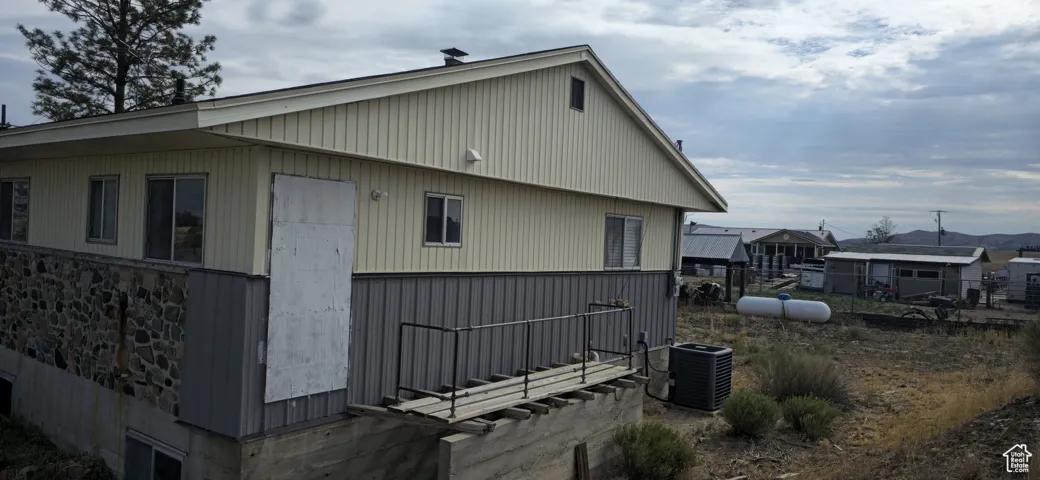 Exterior featuring a stone-clad foundation, vertical vinyl siding, and a metal roof