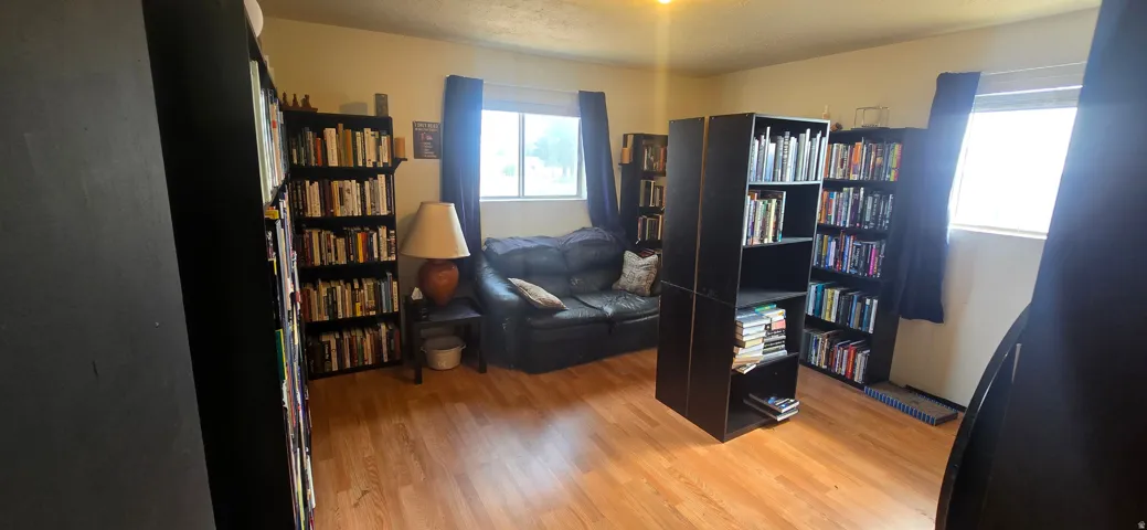 Room featuring wood-finish flooring and multiple windows with dark window treatments