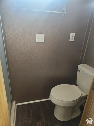 Bathroom with dark wood-finish flooring and textured wall covering