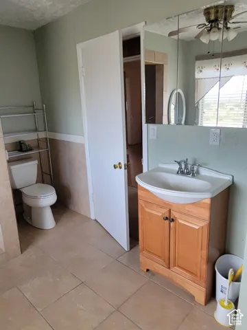 Bathroom featuring a wood-finish vanity with an integrated sink, a mirrored medicine cabinet, and tile flooring