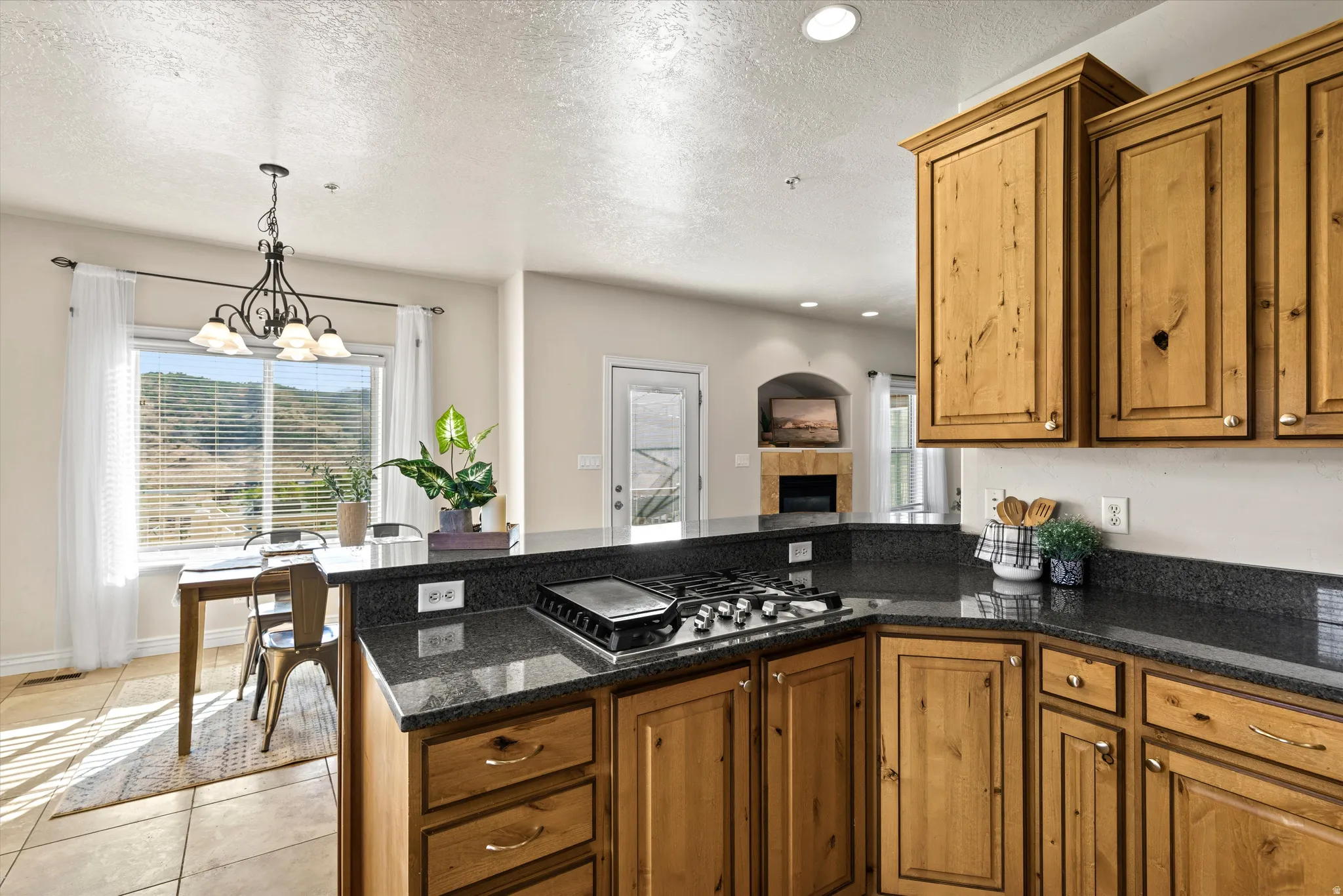 Kitchen featuring wood cabinetry, dark speckled countertops, and an integrated gas cooktop