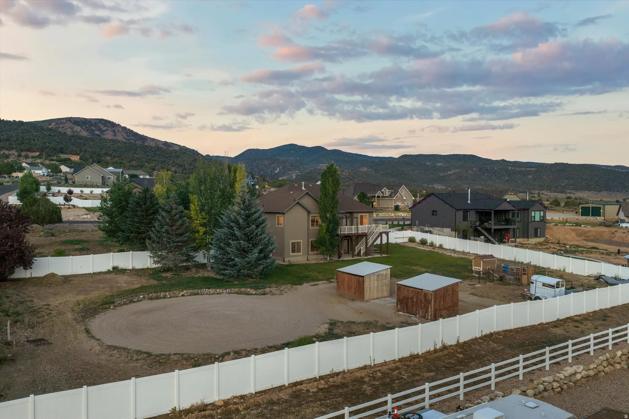 Expansive property featuring a vinyl privacy fence, two detached sheds with metal roofs, and a large cleared area
