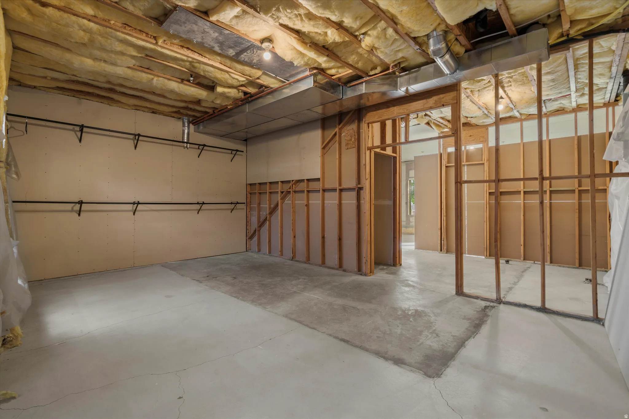 Unfinished basement featuring exposed insulation, wood framing, and a concrete floor