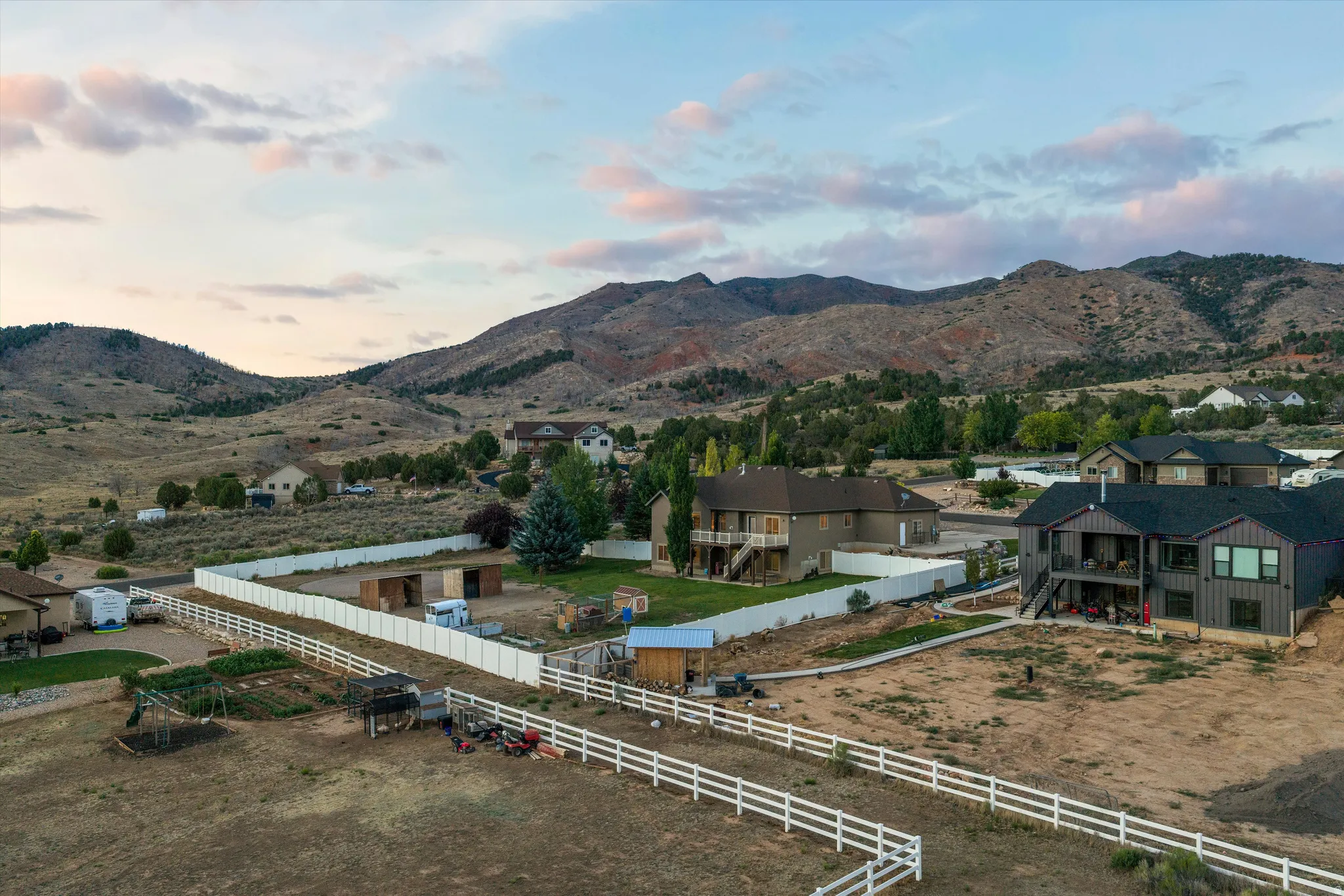 Expansive property featuring a white perimeter fence and distant mountain backdrop