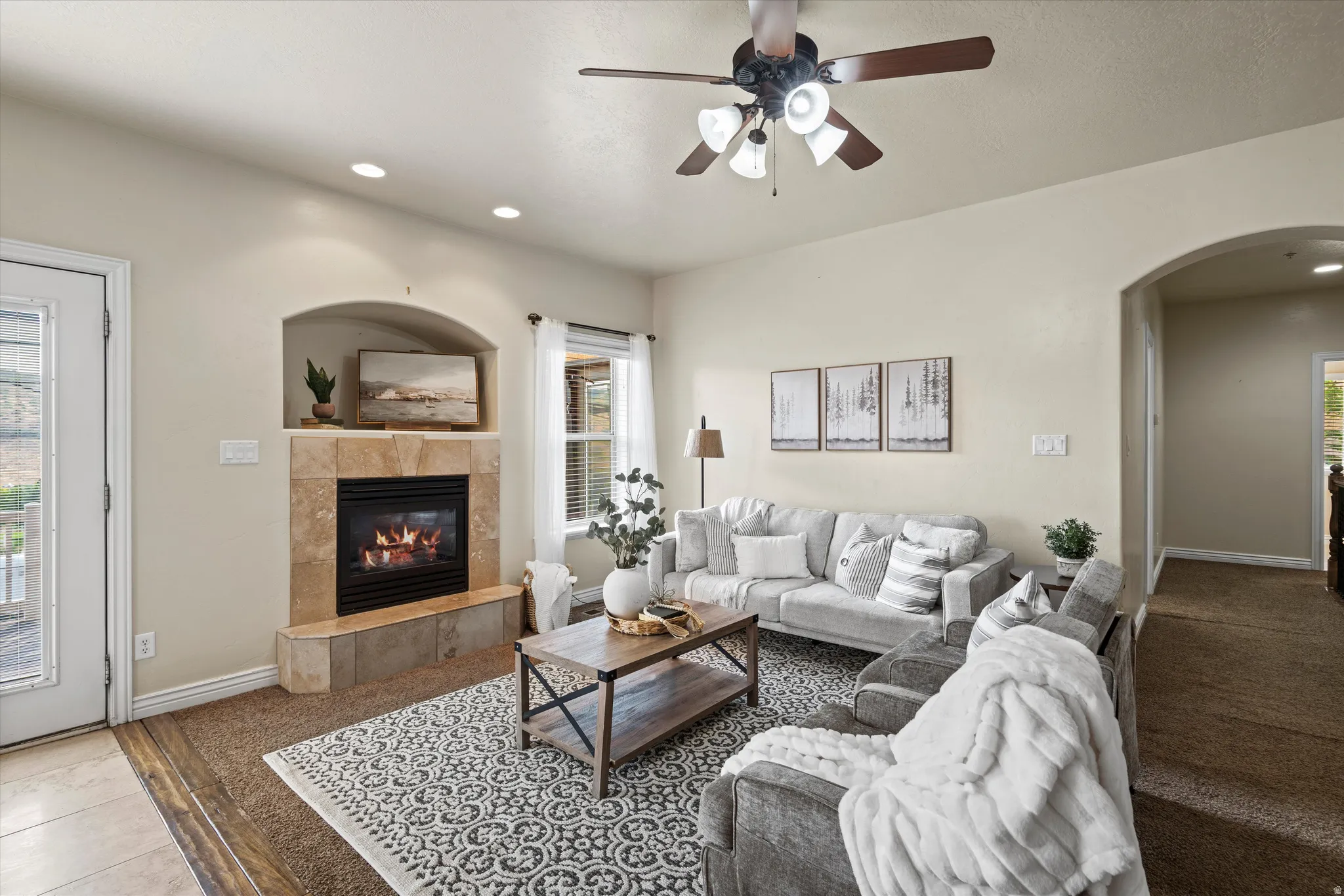 Living area featuring a tiled fireplace with an arched niche, recessed lighting, and a ceiling fan