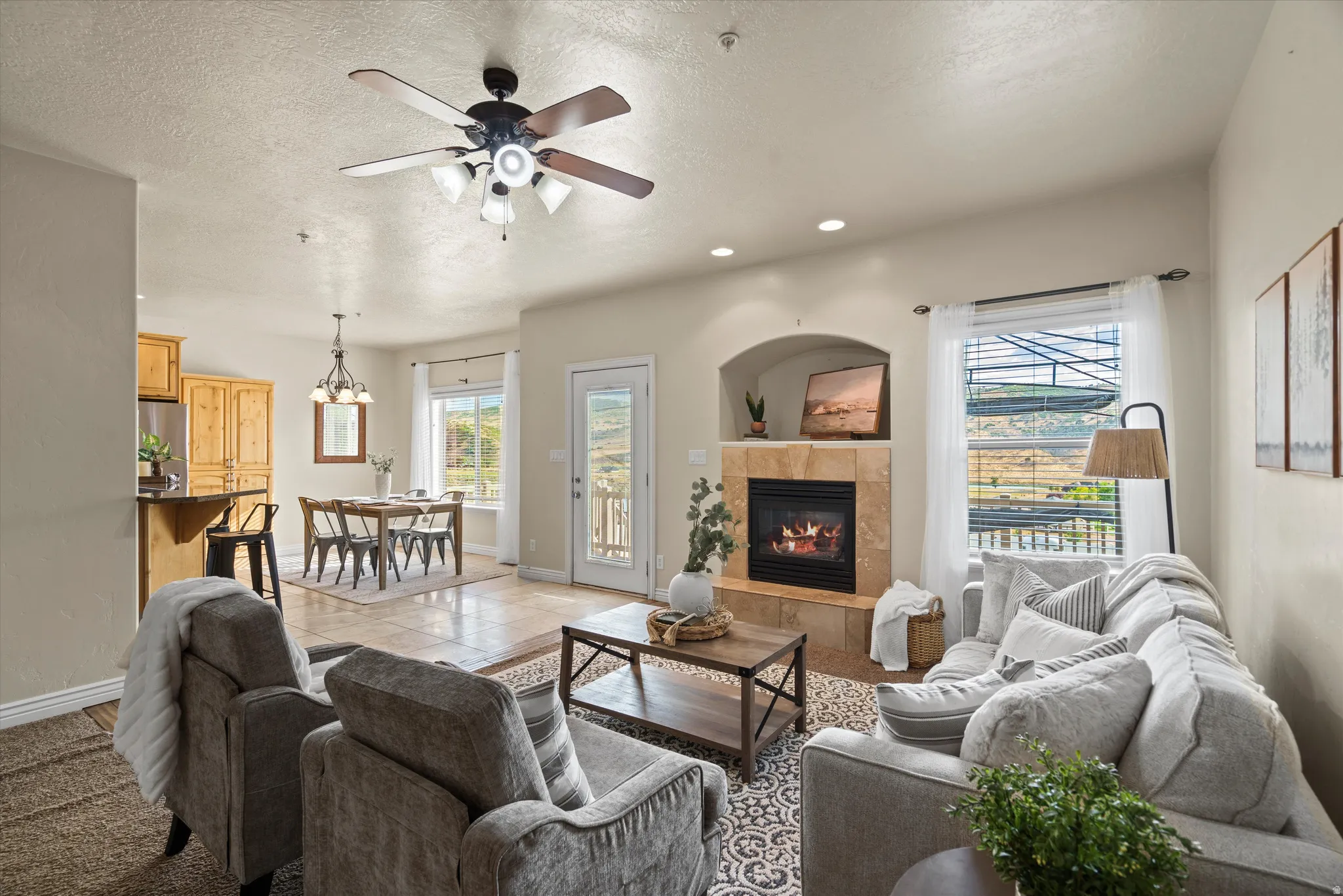 Living area featuring an arched fireplace with stone surround, a ceiling fan with integrated lighting, and recessed ceiling lighting
