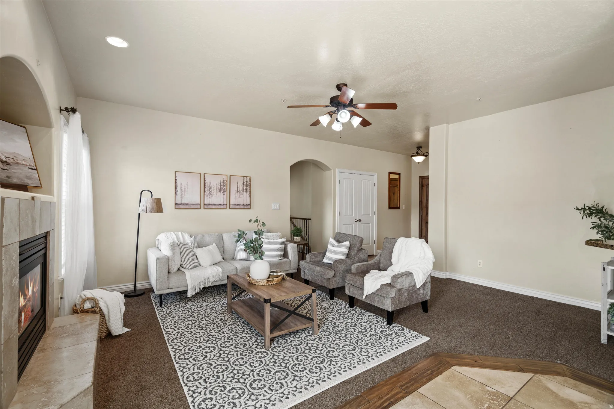 Spacious living area featuring a stone-clad fireplace, arched doorways, a ceiling fan, and recessed lighting