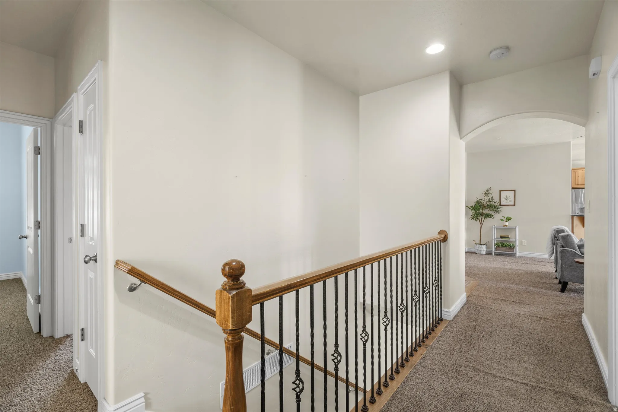 Stairway featuring wood handrails and wrought iron balusters