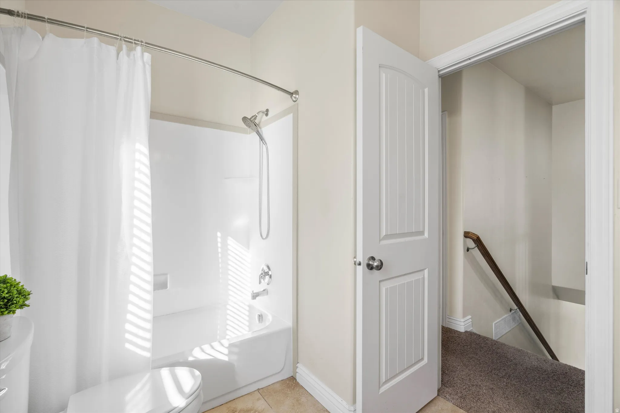 Bathroom featuring a white shower-over-tub combination with chrome fixtures, a curved shower rod, and light-toned wall paint