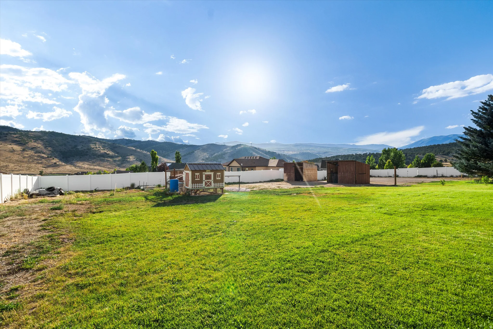 Expansive green lawn with a white privacy fence
