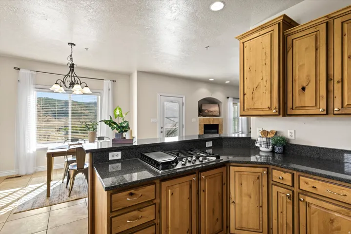 Kitchen featuring wood cabinetry, dark speckled countertops, and an integrated gas cooktop