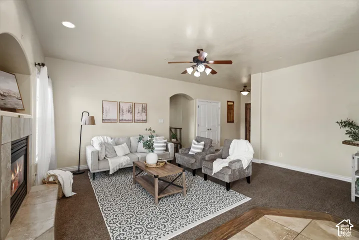 Spacious living area featuring a stone-clad fireplace, arched doorways, a ceiling fan, and recessed lighting