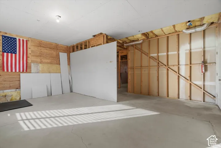 Unfinished interior space featuring exposed wood framing, concrete flooring, drywall sheets, and a ceiling-mounted light fixture