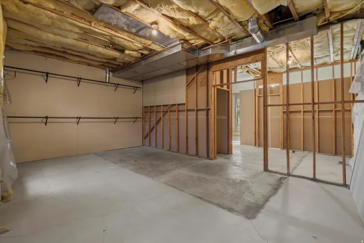 Unfinished basement featuring exposed insulation, wood framing, and a concrete floor