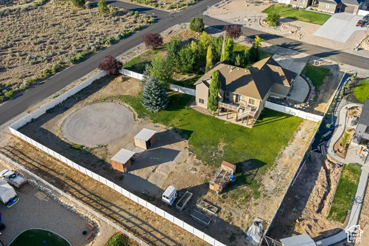 Expansive property featuring a vinyl privacy fence, a circular gravel area, two outbuildings, a multi-level deck, and a manicured lawn