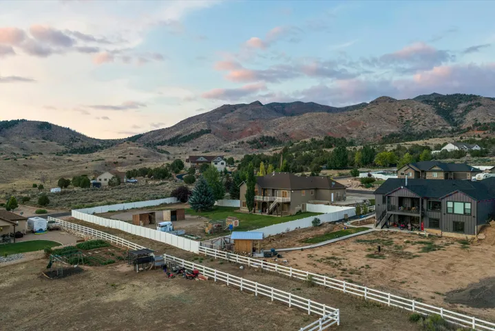 Expansive property featuring a white perimeter fence and distant mountain backdrop