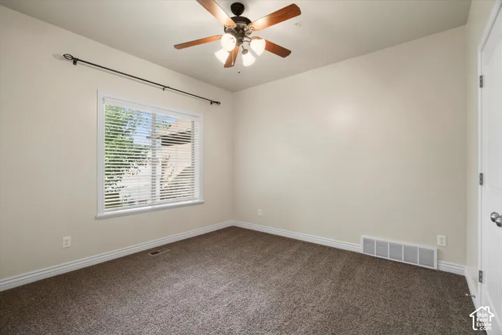 Carpeted room featuring a ceiling fan with light fixture, a window with horizontal blinds, and a white paneled door