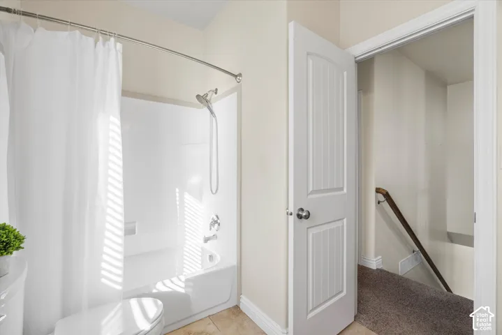 Bathroom featuring a white shower-over-tub combination with chrome fixtures, a curved shower rod, and light-toned wall paint