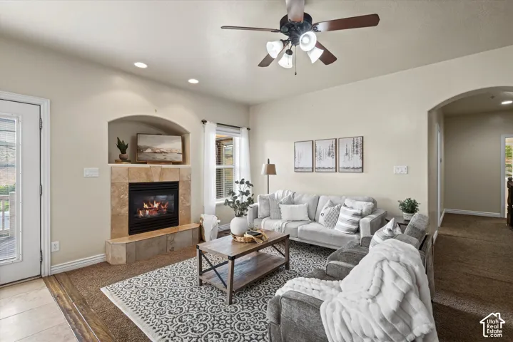 Living area featuring a tiled fireplace with an arched niche, recessed lighting, and a ceiling fan