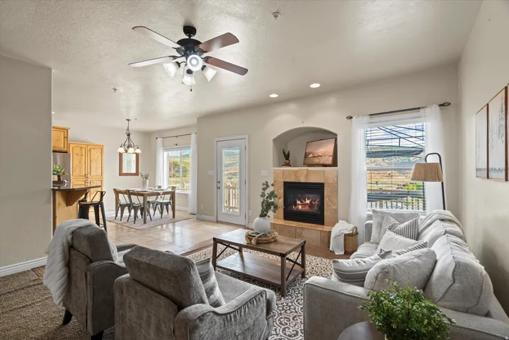 Living area featuring an arched fireplace with stone surround, a ceiling fan with integrated lighting, and recessed ceiling lighting