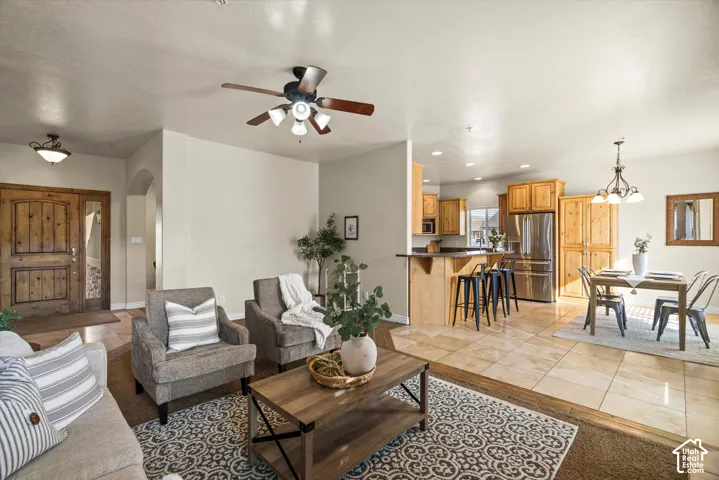 Open-concept living area featuring a wood-finish double entry door, an archway, a ceiling fan, and tile flooring throughout the kitchen and dining areas