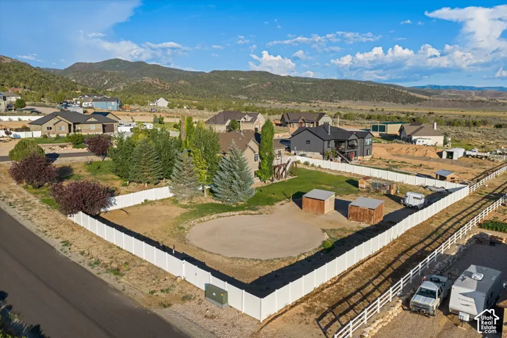 Expansive property featuring a white vinyl perimeter fence, multiple mature trees, and a graded circular area