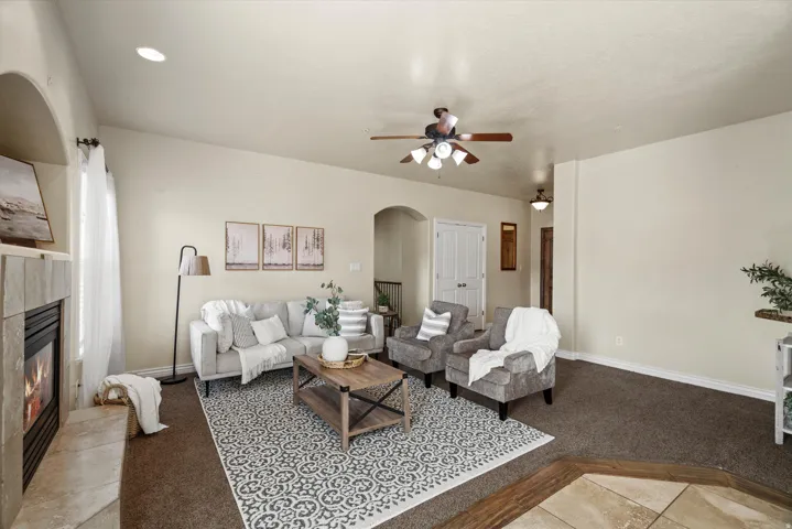 Spacious living area featuring a stone-clad fireplace, arched doorways, a ceiling fan, and recessed lighting