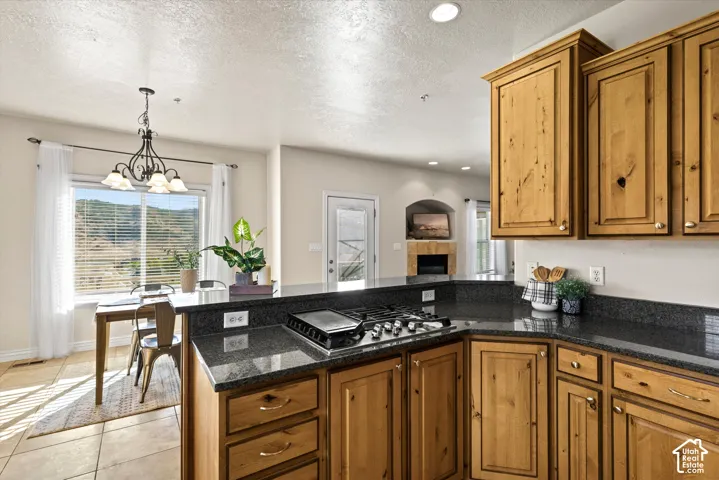 Kitchen featuring wood cabinetry, dark speckled countertops, and an integrated gas cooktop