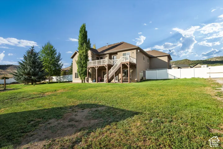 Expansive rear yard featuring a large lawn area, mature trees, and a white privacy fence