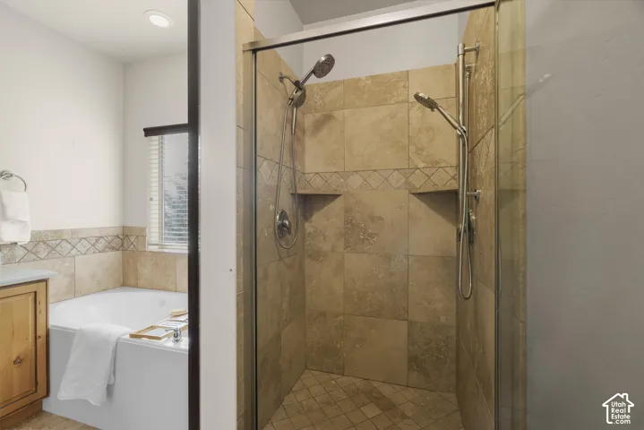 Glass-enclosed shower featuring natural stone tile, dual shower heads, and integrated shelving