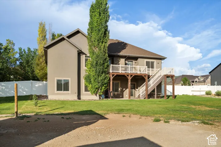 Rear exterior featuring a two-story stucco facade, an upper-level deck with white railings, and a walk-out lower level