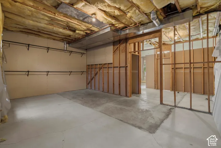 Unfinished basement featuring exposed insulation, wood framing, and a concrete floor