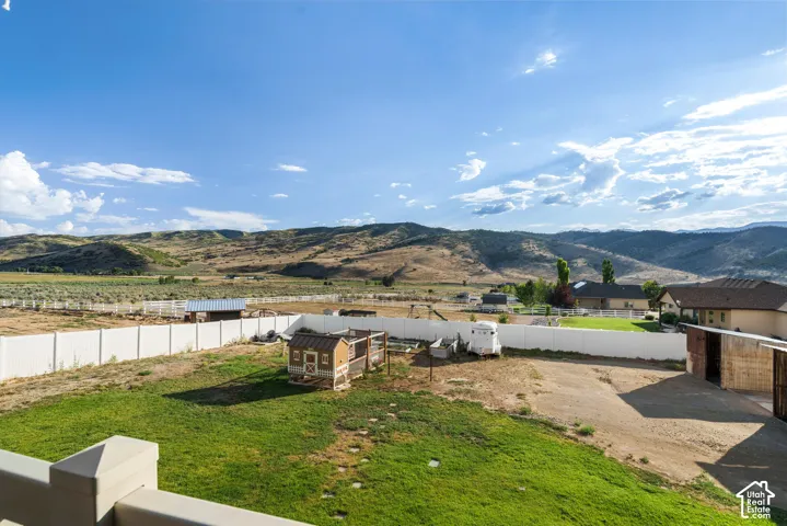 Expansive property featuring a vibrant green lawn area, a white perimeter fence, and a distant mountainous backdrop