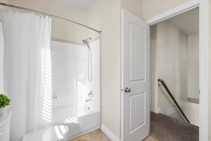 Bathroom featuring a white shower-over-tub combination with chrome fixtures, a curved shower rod, and light-toned wall paint