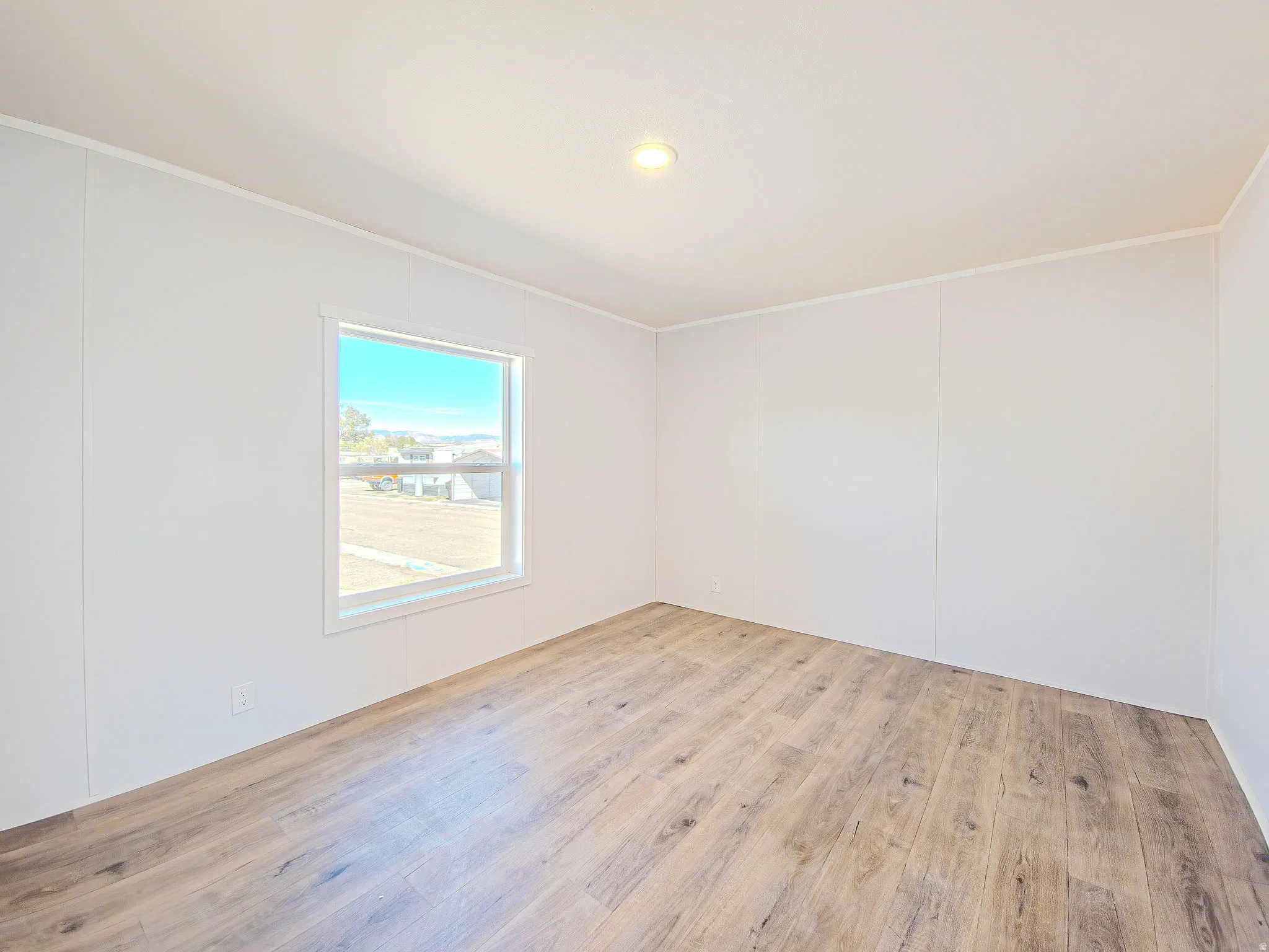 Wood-finish flooring, recessed ceiling light, white trim, and a window with a white frame