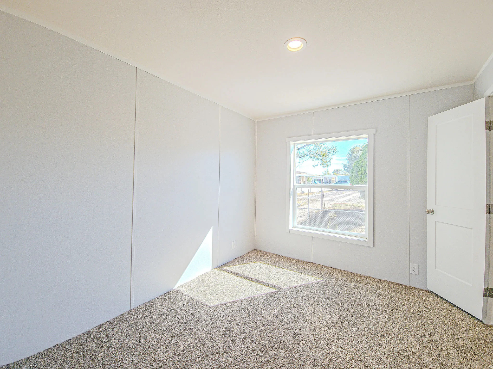 Recessed ceiling lighting, white interior door, white window trim, and carpeted flooring