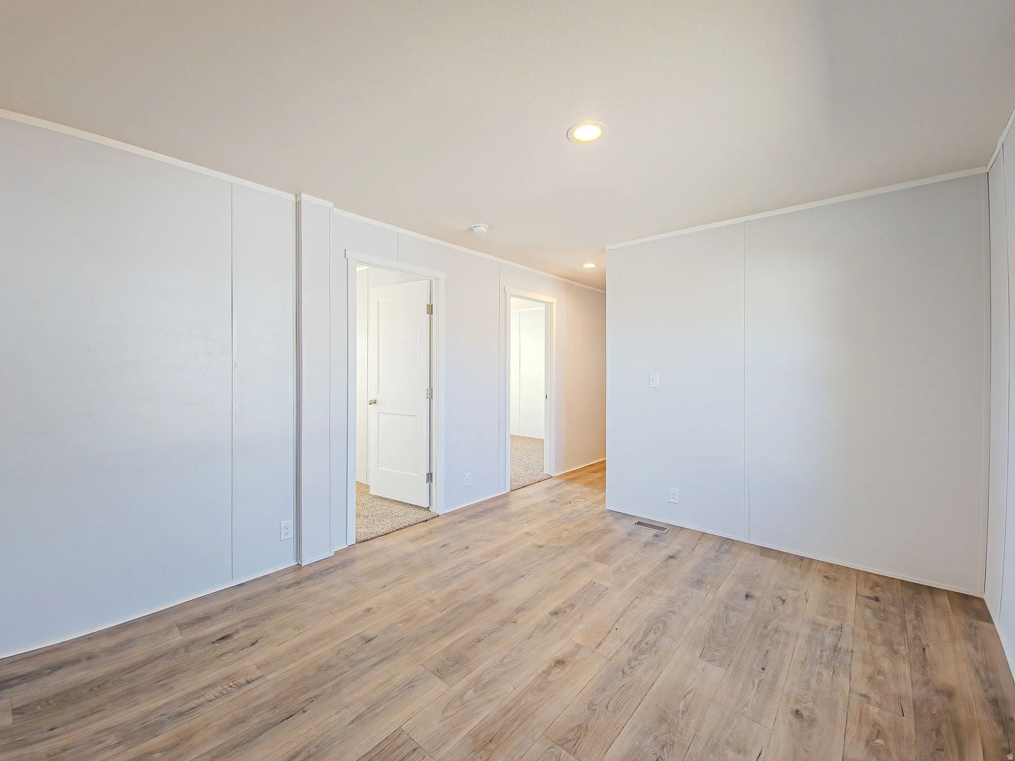 Wood-finish flooring, recessed ceiling lighting, and white paneled walls