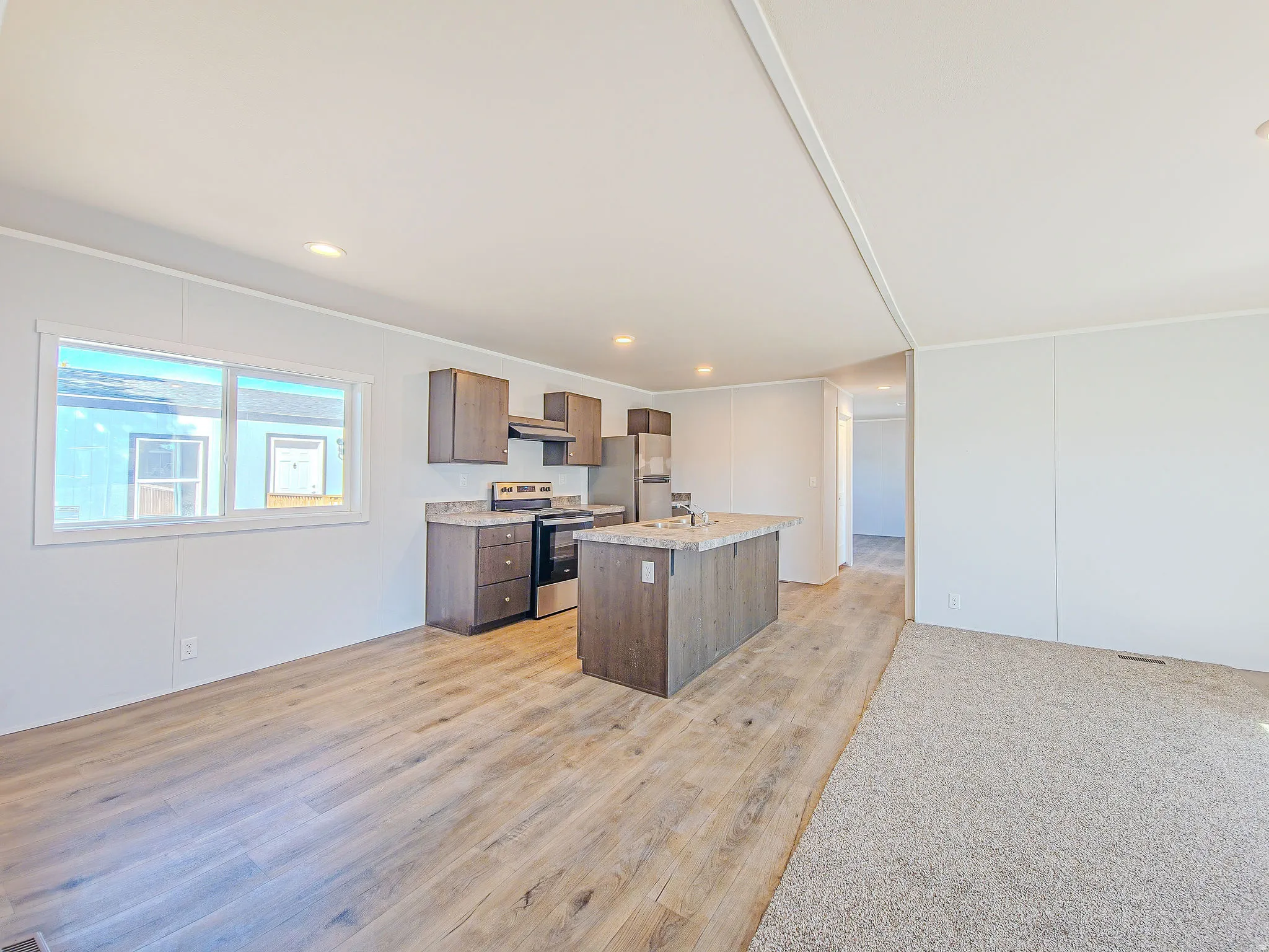 Open-concept living space featuring wood-finish flooring, recessed lighting, and a kitchen island with seating