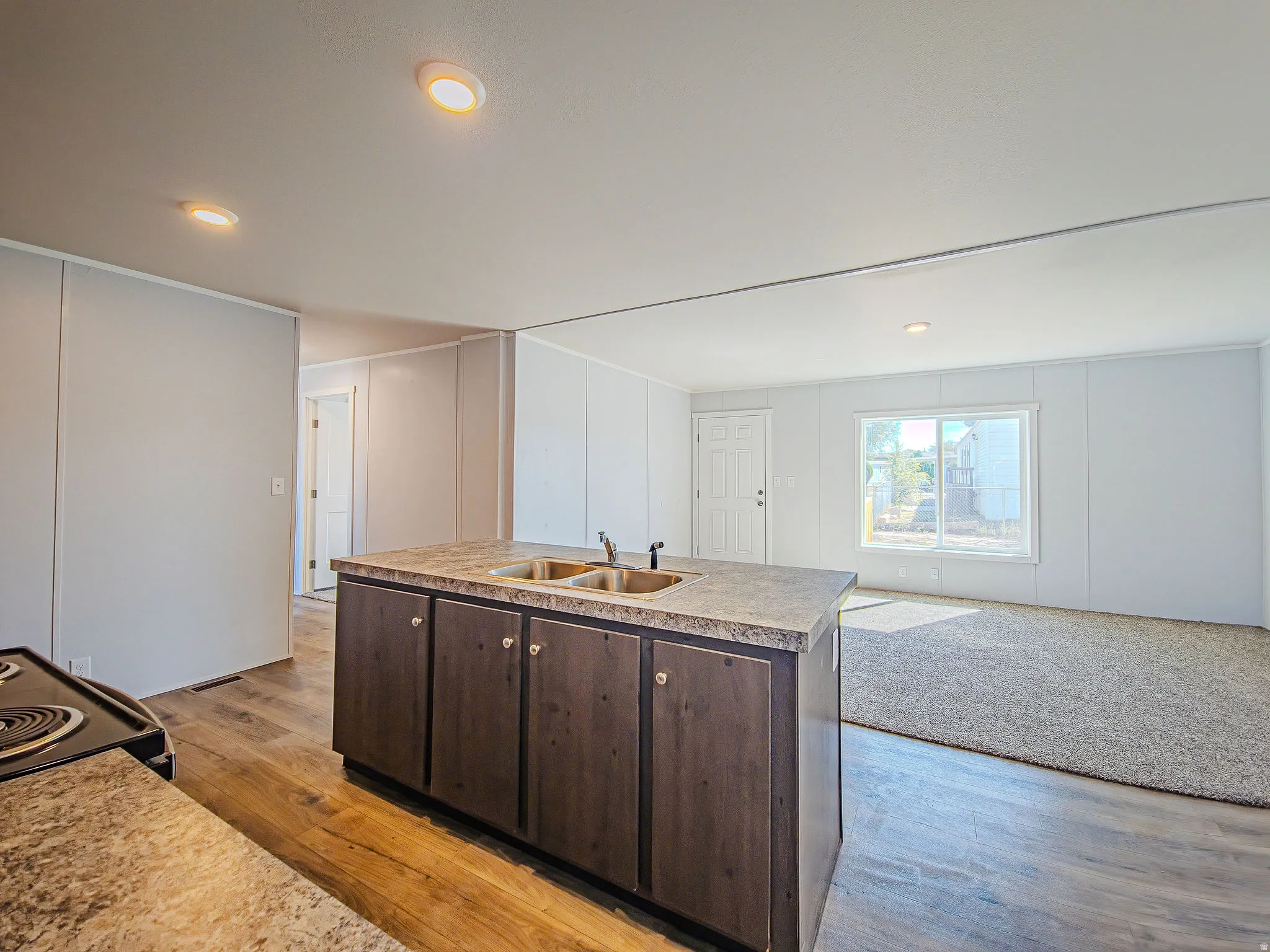 Kitchen island with integrated double basin sink and dark wood-finish cabinetry