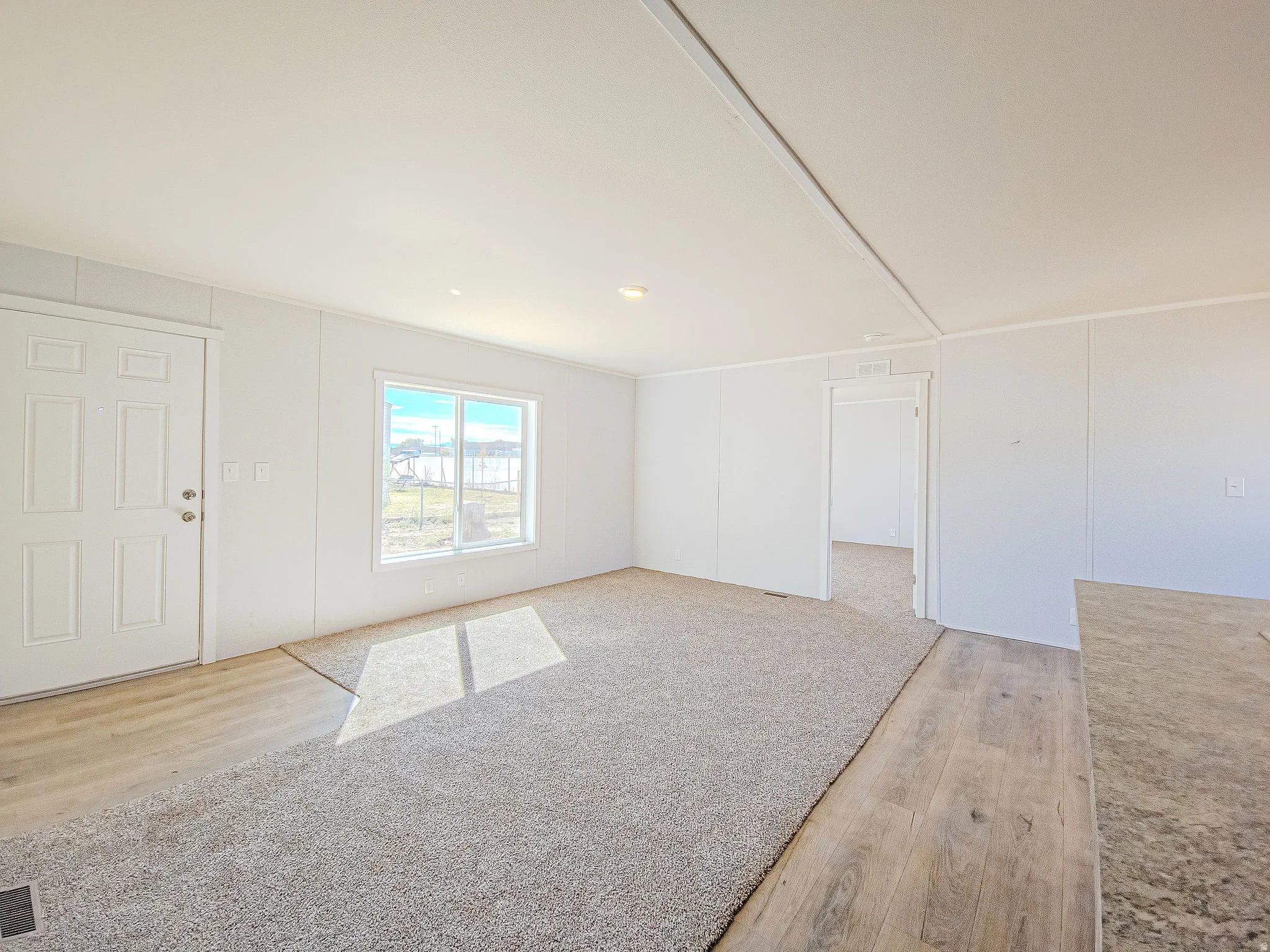 Hardwood-finish flooring, neutral carpeting, white interior doors, and a window with natural light