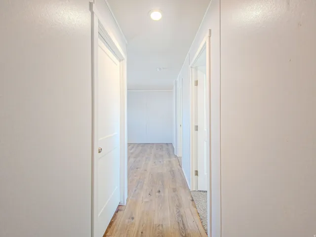 Hallway with wood-finish flooring and multiple white doors