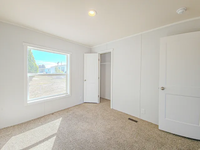 Recessed ceiling lighting, white panel doors, neutral carpeting, and a window with white trim