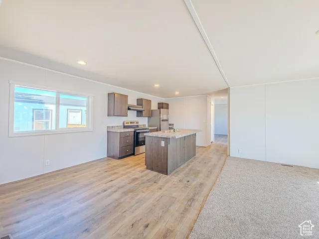 Open-concept living space featuring wood-finish flooring, recessed lighting, and a kitchen island with seating